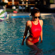 A woman in a red swimsuit is standing in a pool.