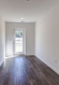 a living room with white walls and wood flooring and a door