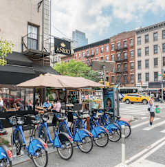 A row of blue bikes are parked on the side of a street.