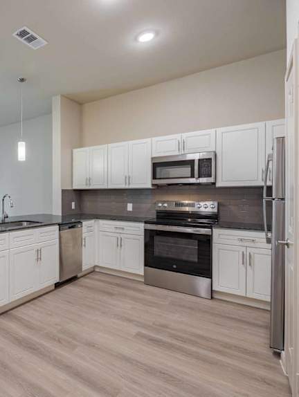 A kitchen with a checkered floor and a brick wall.