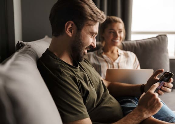 a man and a woman sitting on a couch looking at their cell phones