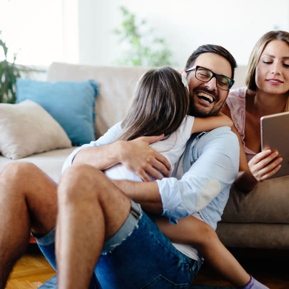 a man and two women sitting on a couch looking at a tablet