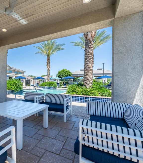 A patio with a white couch, a fireplace, and a television. at Vistoria At Marley Park Apartments, Arizona