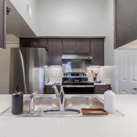 A modern kitchen with a double sink and a stainless steel refrigerator.