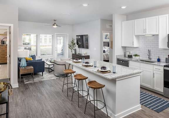 a kitchen and living room with an island and bar stools at Century Mundy Mill Apartments, Georgia