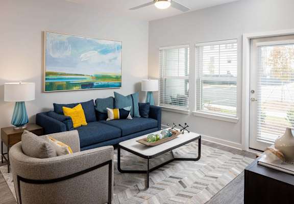 a living room with a blue couch and a coffee table at Century Mundy Mill Apartments, Georgia 30566