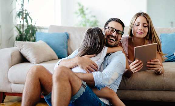 a man and two women sitting on a couch looking at a tablet