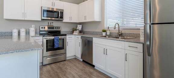 A kitchen with white cabinets and stainless steel appliances. at Vistoria At Marley Park Apartments, Arizona