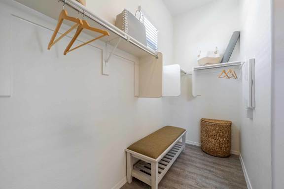 A small room with a bed, a bench, and a small refrigerator. at Vistoria At Marley Park Apartments, Arizona