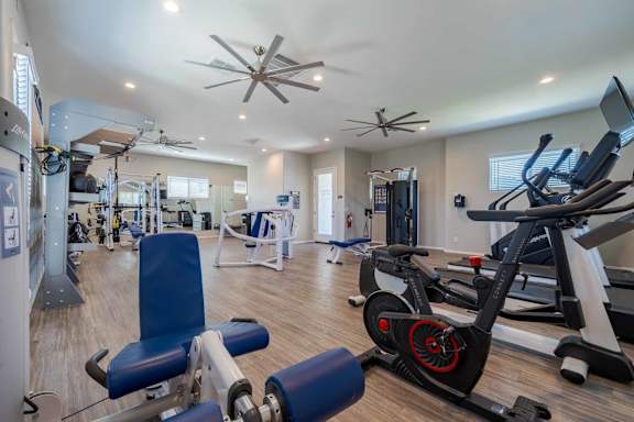A spacious gym with a variety of equipment including treadmills, weights, and a rowing machine.