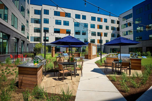 an outdoor patio with tables and umbrellas in front of an apartment building at Dey & Bergen, Harrison, 07029