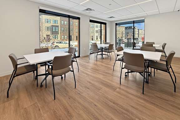 A spacious room with wooden flooring and large windows.