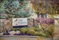 A sign that says "The Pointe" in front of a bush.