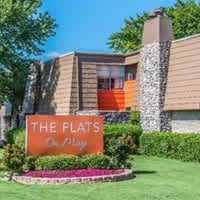 A sign that says "The Flats on May" in front of a building.
