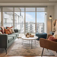 A living room with a grey couch, a white coffee table, a blue ottoman, and a brown chair.