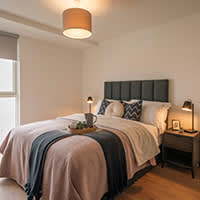 A bed with a white comforter and a black headboard with a tray on it.