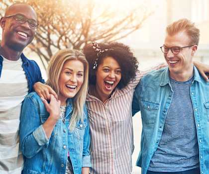 A group of five friends are standing together outside.