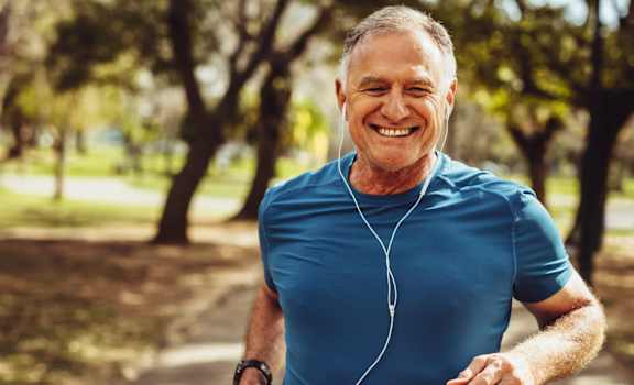 A man in a blue shirt is jogging in a park.
