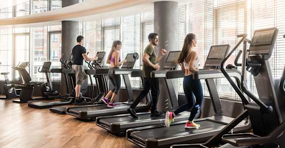 a group of people walking on treadmills in a gym
