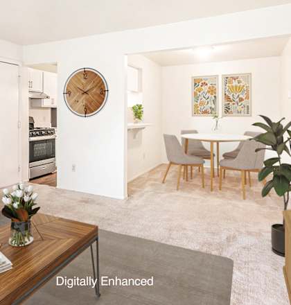 A living room with a grey couch, a wooden coffee table, and a painting on the wall at West Wind Apartments, Fort Wayne, IN
