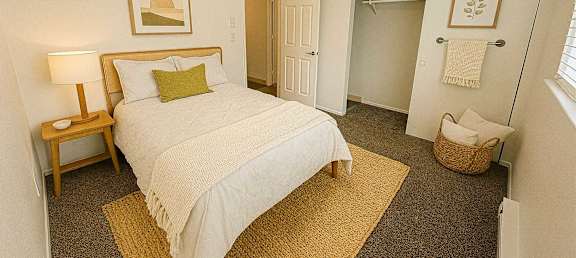 A bedroom with a bed, nightstand, and a basket on the floor.