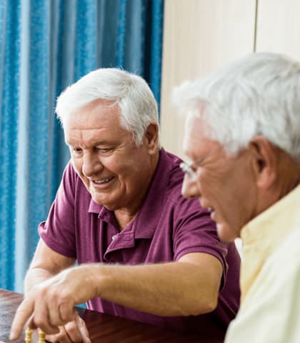 Four elderly people playing chess together.