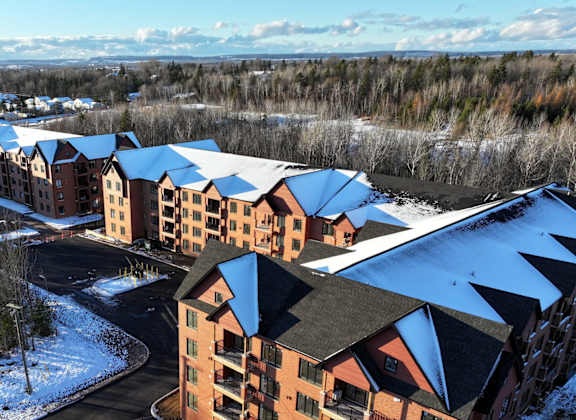 A large building complex with snow on the ground and trees in the background.
