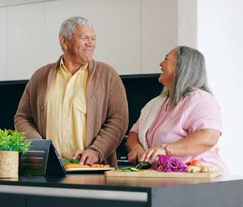 a man and a woman standing in a kitchen preparing food