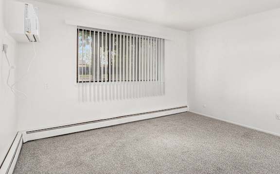 A room with a window covered by vertical blinds