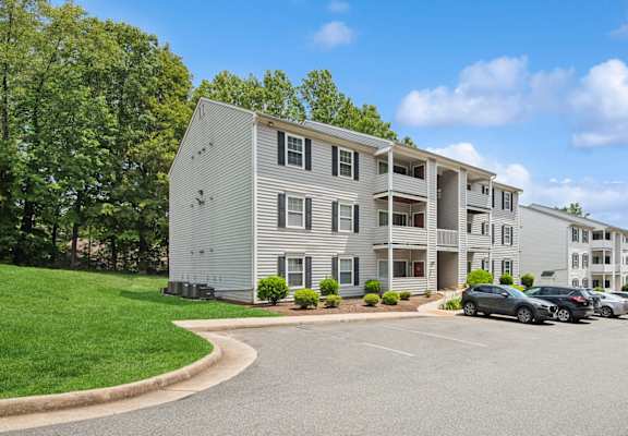 A large white apartment building with a parking lot in front of it.