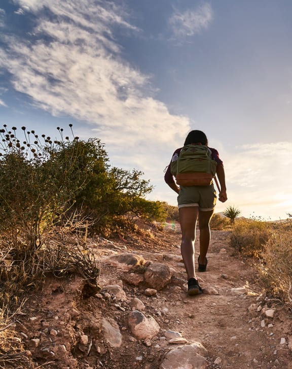 a woman with a backpack walking on a trail