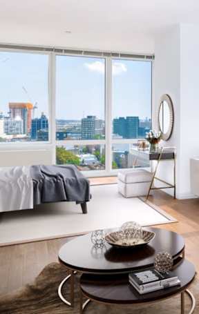 A modern living room with a view of the city at The Maximilian Apartments, New York, 11101