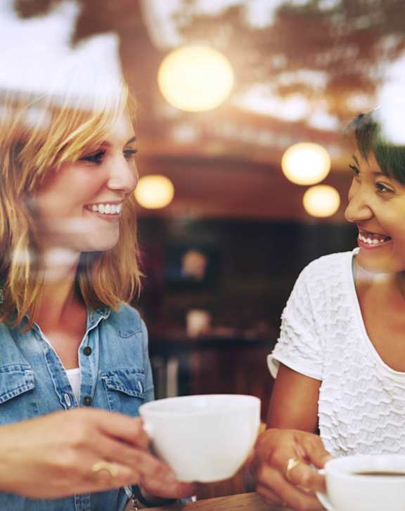 Two women having a conversation over coffee in a cafe.