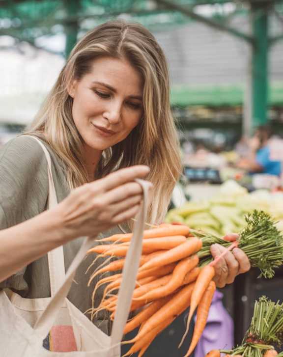 A woman is shopping for vegetables at a market.