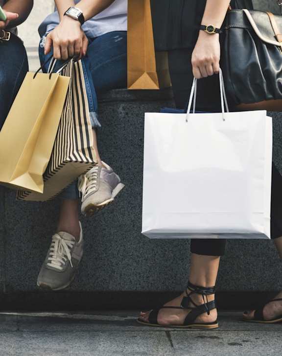 A group of people sitting on a bench with shopping bags.