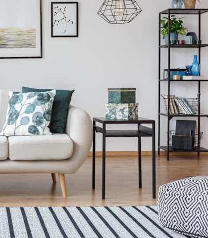 A living room with a white sofa, a small table, and a plant.
