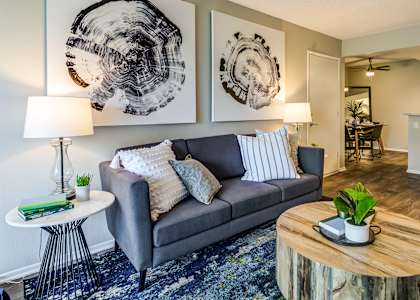 A living room with a grey couch, a wooden coffee table, and two abstract art pieces on the wall.
