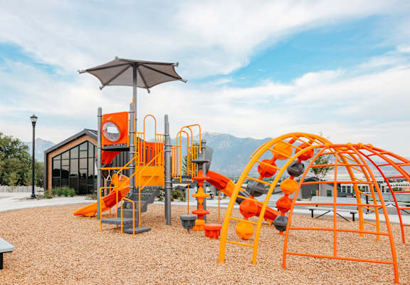A playground with orange and black equipment and a bench.