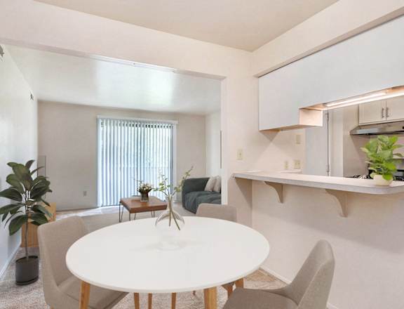 A white dining table with chairs and a potted plant in a room at West Wind Apartments, Fort Wayne, IN