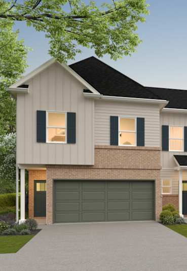 A two-story house with a garage is surrounded by greenery.