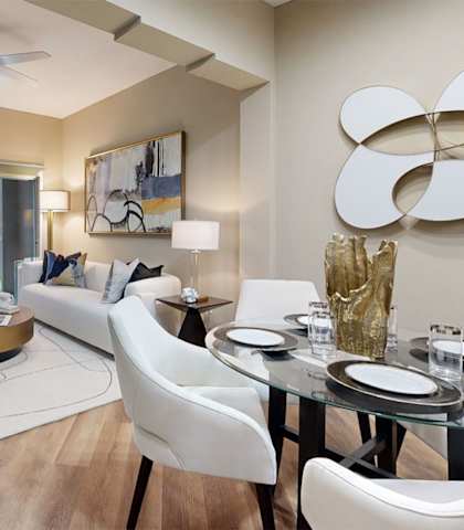 A modern living room with a glass table and white chairs.