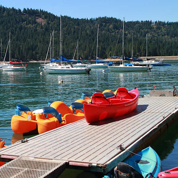 A dock with a red kayak on it and boats in the water.