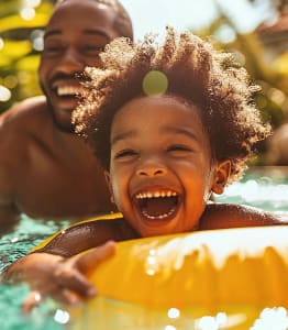 a family sitting on the edge of a swimming pool with their hands in the air