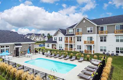 a swimming pool with lounge chairs in front of apartment buildings