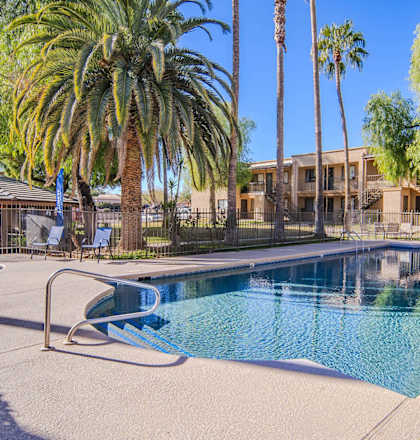 a swimming pool with palm trees and a building in the background