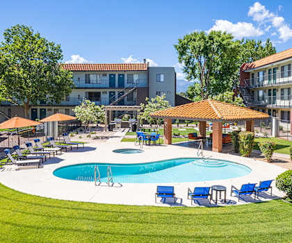 A swimming pool surrounded by lawn chairs and umbrellas.