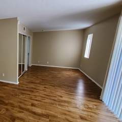 A room with wooden flooring and a window on the right side.