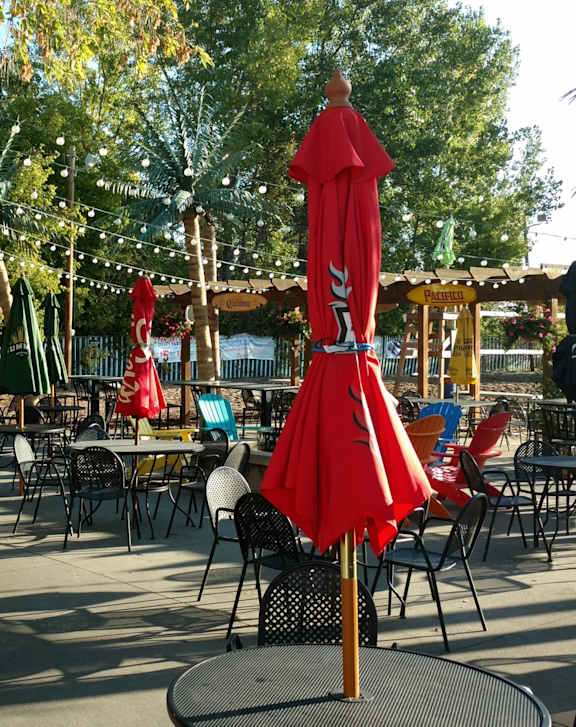 A red umbrella stands out in a sunny outdoor cafe.
