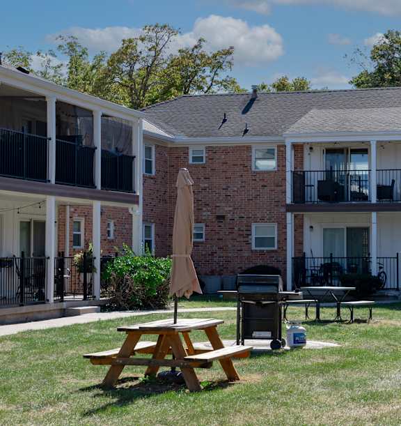 A sunny day at a brick apartment complex with a picnic table in the foreground.