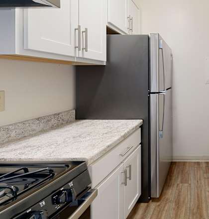 A kitchen with a black refrigerator and a stove top oven.